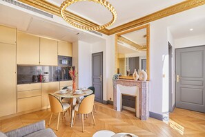 A modern kitchen with a dining area, a fireplace, and a large mirror. - Superb AC- 2bdr Apartement Montaigne/arc de Triomphe (Paris)