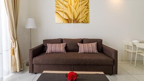 A living room with a brown sofa, two striped pillows, a white floor lamp, and a wall-mounted artwork of yellow leaves. - A Place Define Happiness in M Suite Klcc (Kuala Lumpur)