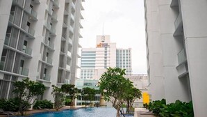 A modern building with a swimming pool, surrounded by greenery and adjacent to taller buildings. - A Place Define Happiness in M Suite Klcc (Kuala Lumpur)