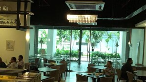 An indoor dining area with tables and chairs, large windows, and a chandelier. - A Place Define Happiness in M Suite Klcc (Kuala Lumpur)