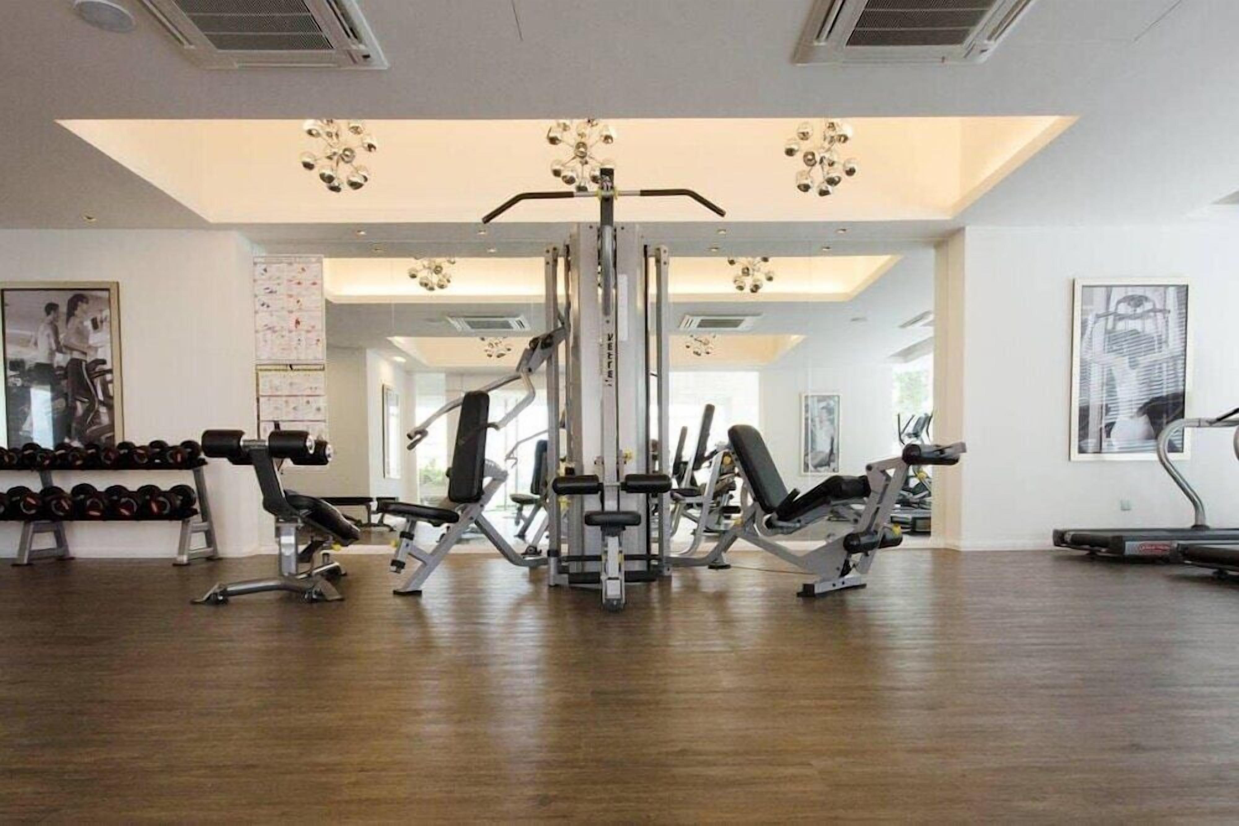 A gym with various exercise equipment, including dumbbells, benches, and a weight machine.