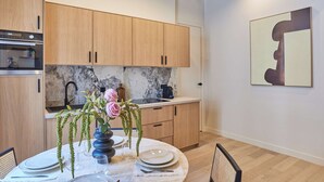A modern kitchen with wooden cabinets, a marble countertop, and a dining area with a round table set for four. - Charming Apartment in the Center of Paris (Paris)