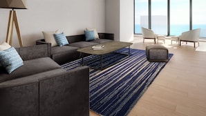 Ein modernes Wohnzimmer mit einer Couch, Sesseln, einem Couchtisch und einer Lampe.