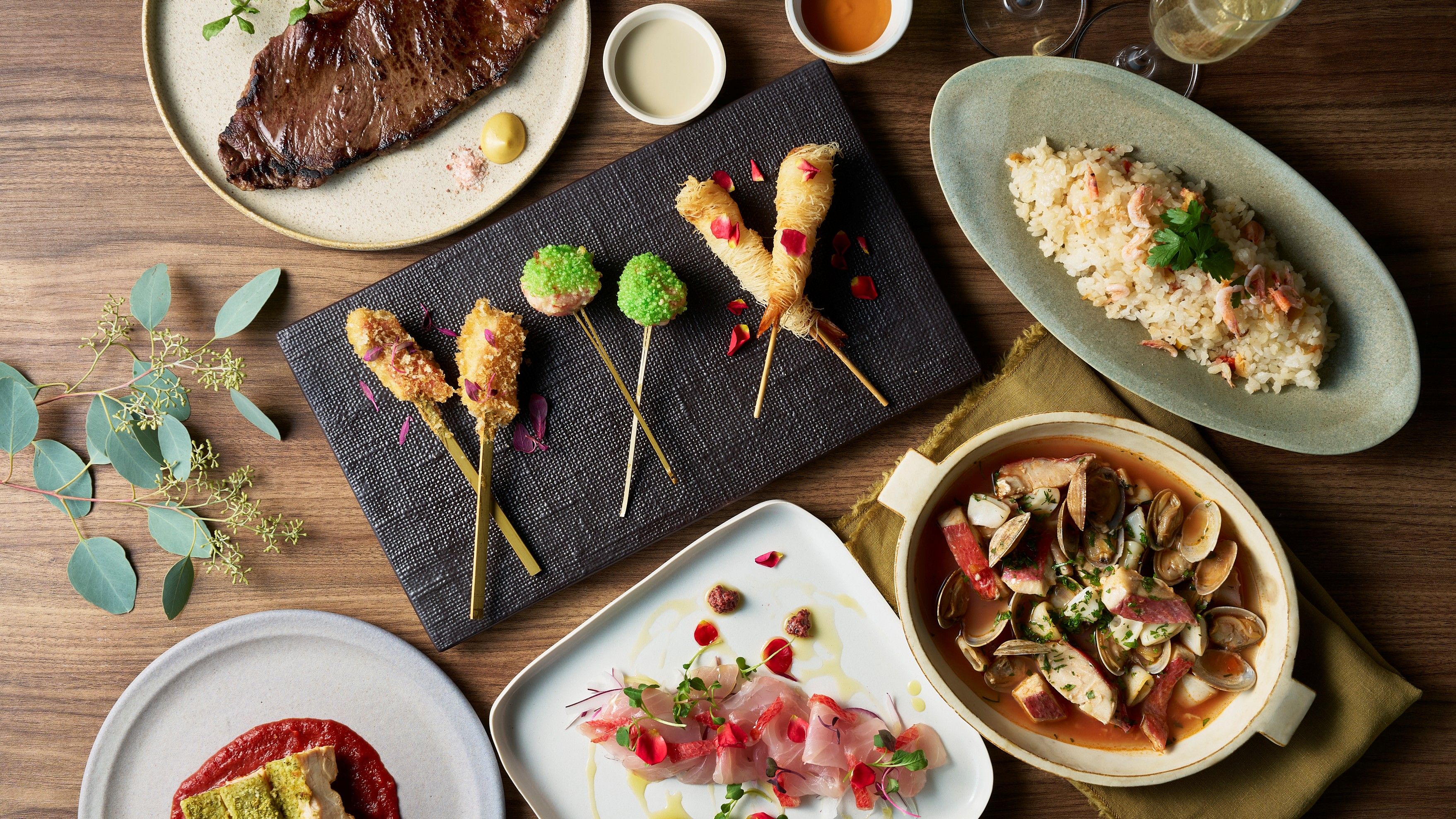 A variety of dishes including seafood, rice, and a steak, suggesting a fine dining experience.
