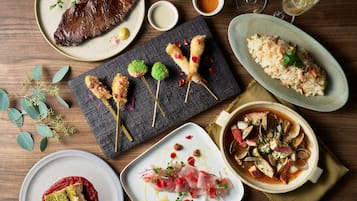 Variedad de platillos, entre ellos mariscos, arroz y un corte de carne, evocando una experiencia culinaria de alta calidad.