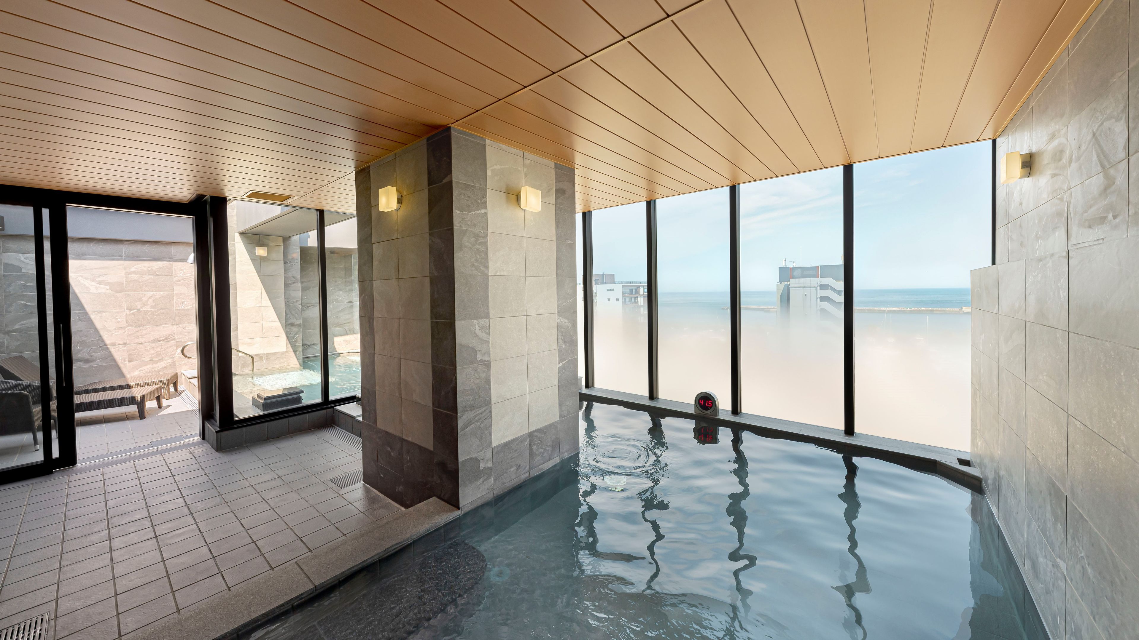 A modern indoor pool area with clear views of the beach and ocean.