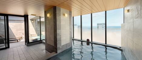 A modern indoor pool area with clear views of the beach and ocean.
