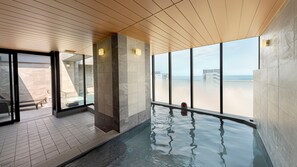 A modern indoor pool area with clear views of the beach and ocean. - Village Atami (Atami)