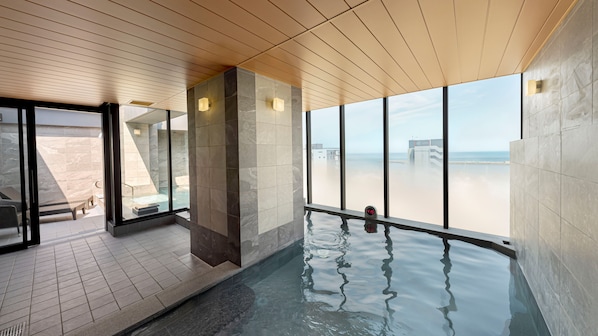 A modern indoor pool area with clear views of the beach and ocean.