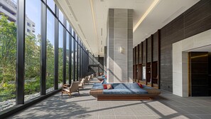 A modern interior with large windows, a seating area with sofas and chairs, and a view of greenery outside. - Village Atami (Atami)