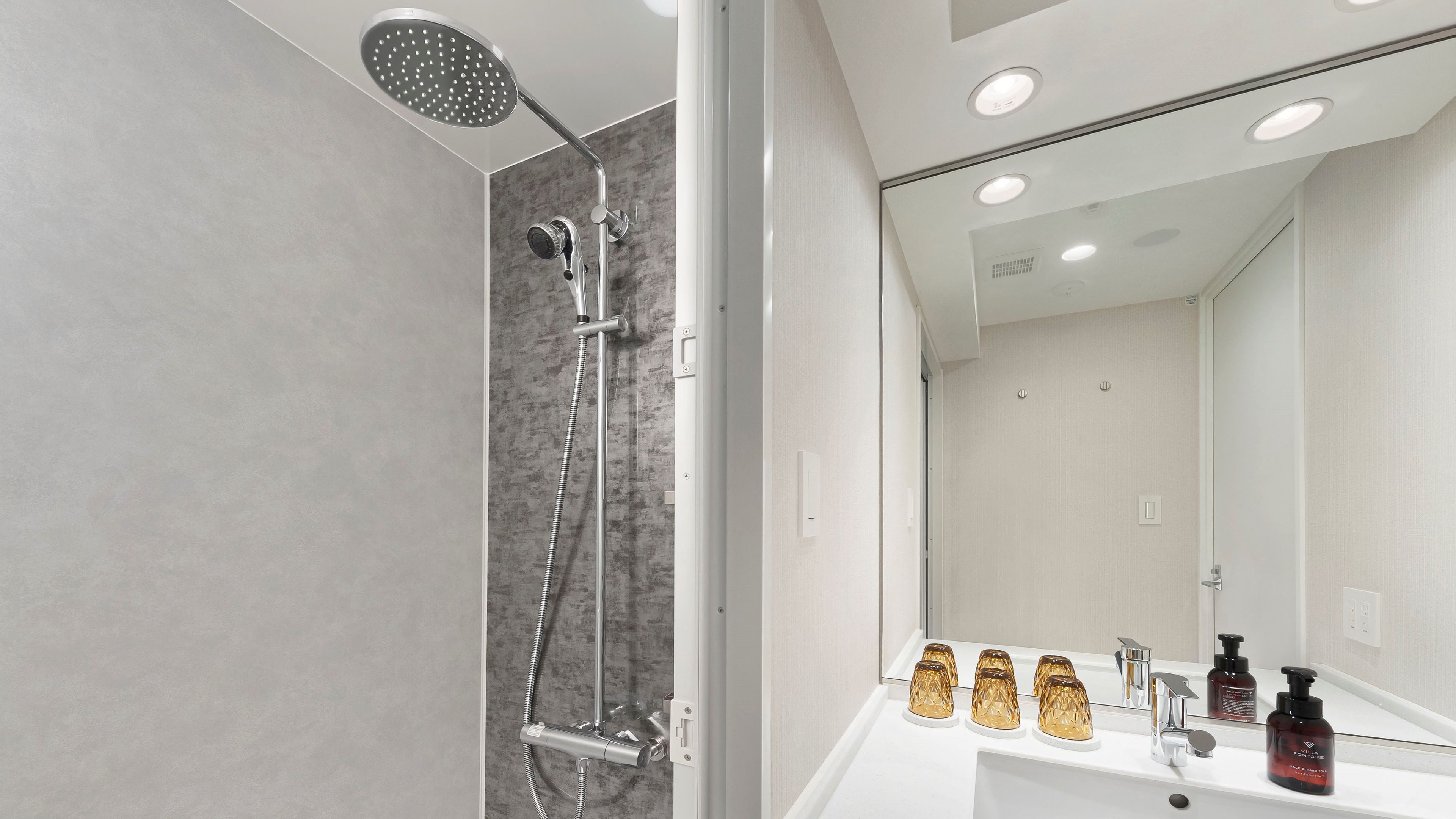 Un baño moderno con ducha, lavamanos y espejo.
