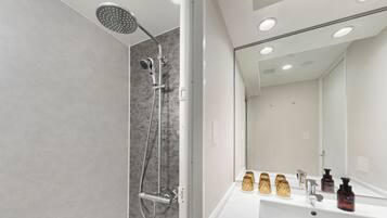 Un baño moderno con ducha, lavamanos y espejo.