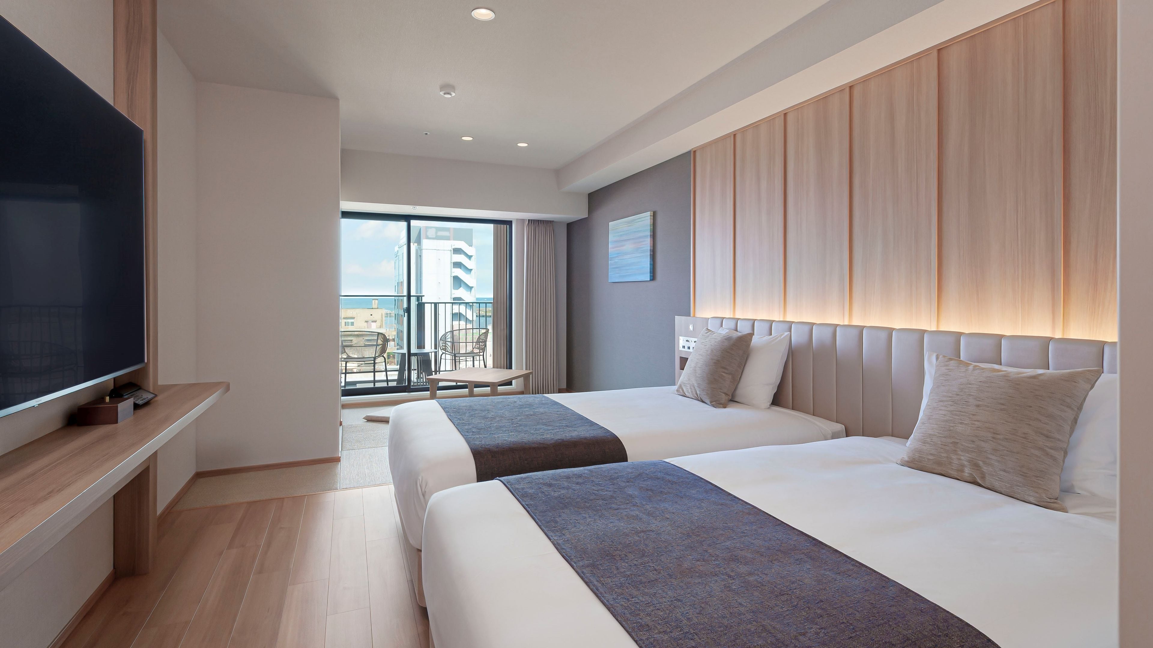 A hotel room with two beds, a TV, a balcony with a view, and a modern design.