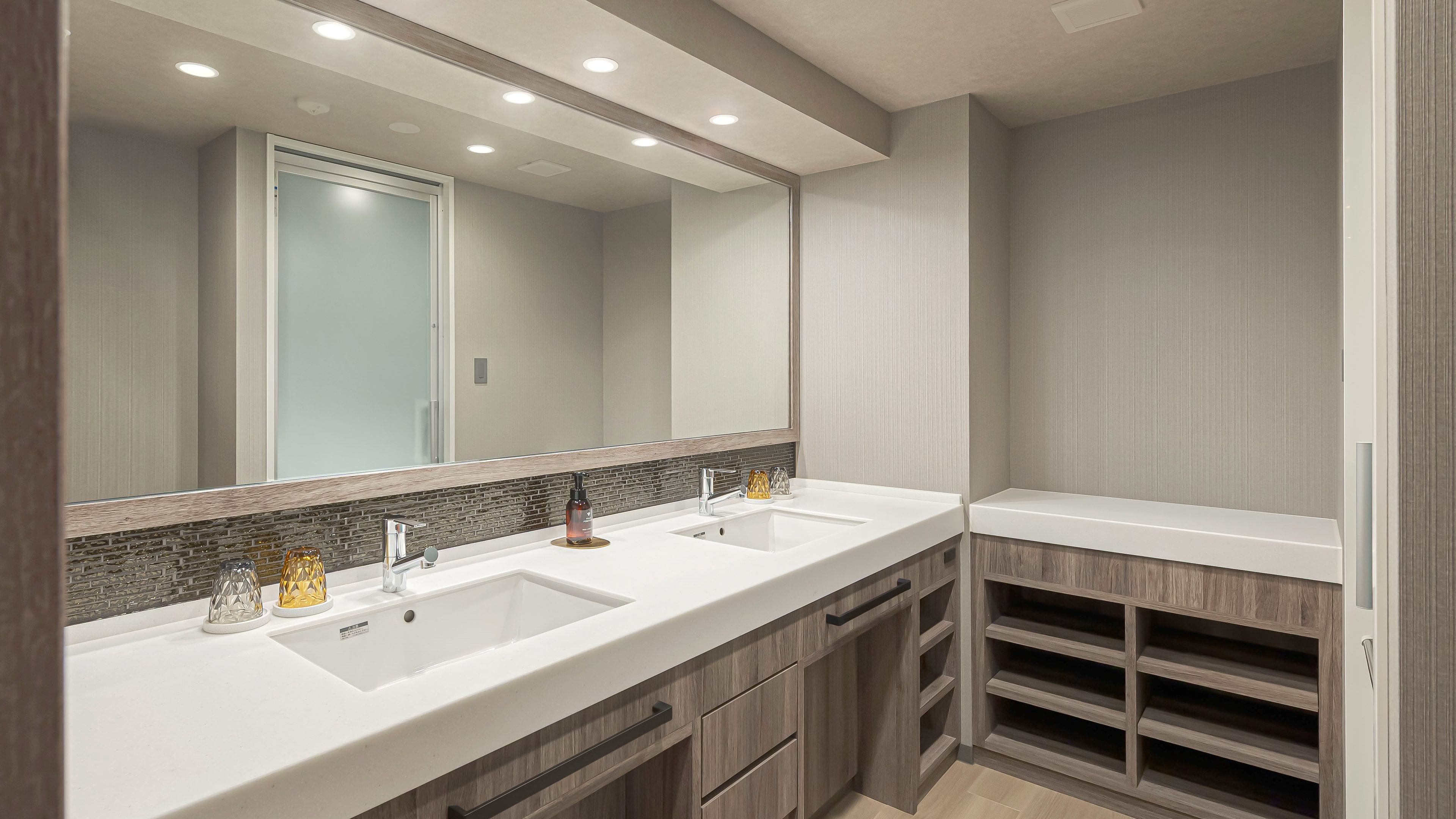 Un baño moderno con dos lavamanos, un espejo grande y armarios empotrados de madera.