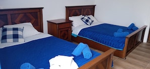 Due letti matrimoniali con testiere in legno, un comodino e biancheria da letto blu.