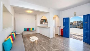 Un interior moderno con zona de estar, una mesita y vistas a través de una puerta abierta.