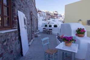 A narrow courtyard with a white table and chairs, surrounded by white buildings with balconies. - Villa Ariadni (Santorini)