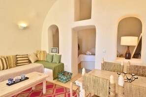 Una habitación con sofá, una mesa de comedor con velas, una lámpara y vistas a través de un arco.