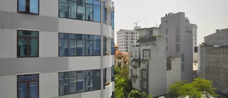 A multi-story building with large windows and balconies, surrounded by other buildings and greenery.