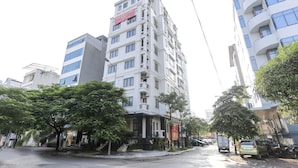 A multi-story building with a prominent red banner advertising furnished apartments for rent. - Poonsa Duy Tan (Hanoi)