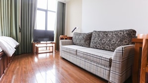 A living room with a sofa, a TV on a stand, and a window with curtains. - Poonsa Duy Tan (Hanoi)