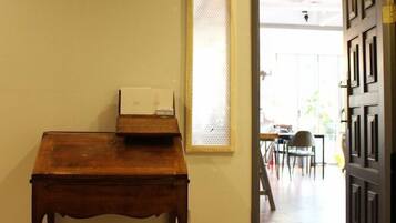 A hallway with a wooden table, a door, and a window with blinds.