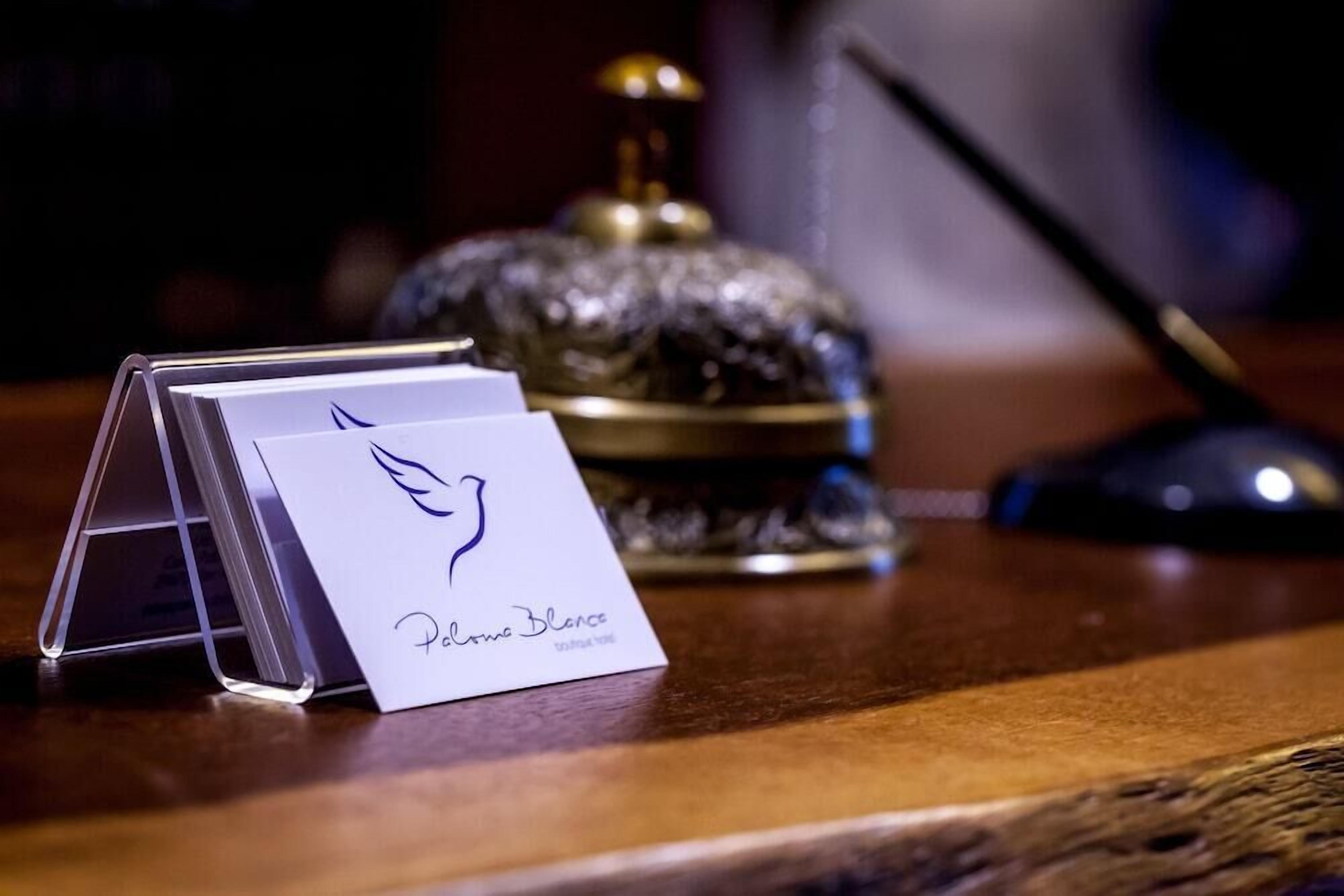 A white card with a logo and text on a wooden surface, a decorative glass object, and a black object in the background.