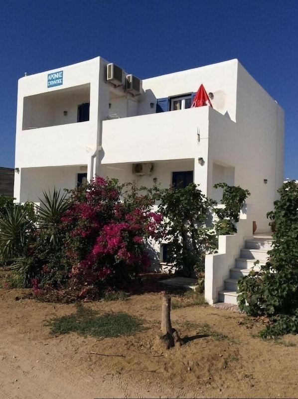 Un edificio blanco de dos pisos con un letrero azul en la esquina superior izquierda.