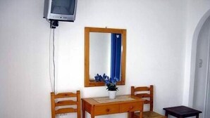 A small room with a wooden desk, two chairs, a mirror, and a television. - Aronis (Naxos)