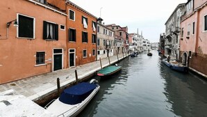 A narrow canal flanked by historic buildings with waterway access for boats. - Bluesky (Venice)