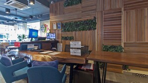 A reception area with a wooden desk, two computer monitors, a plant, and a sign indicating online reservation check-in. - OYO 417 Raintree Boutique Hotel (Kajang)