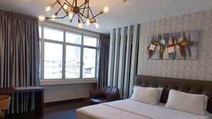 A hotel room with a large bed, a desk, a chair, and a window with curtains. - OYO 417 Raintree Boutique Hotel (Kajang)
