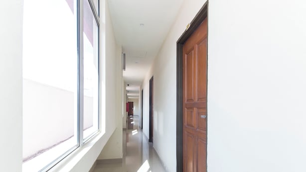 A long, narrow hallway with a wooden door on the right and large windows on the left. - OYO 417 Raintree Boutique Hotel (Kajang)