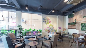 A modern cafe interior with seating arrangements, decorative wall art, and potted plants. - OYO 417 Raintree Boutique Hotel (Kajang)