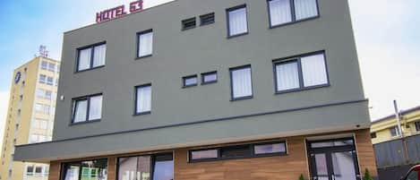 Un edificio moderno de hotel con fachada plana, múltiples ventanas y un letrero que indica que es un hotel.