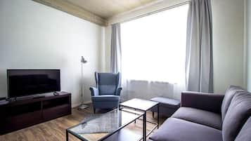 Una sala de estar moderna con un televisor de pantalla plana, un sillón azul, un sofá y una mesa de centro.