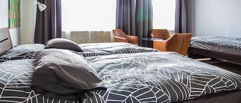 Quarto de hotel com duas camas, uma cadeira e uma mesa.