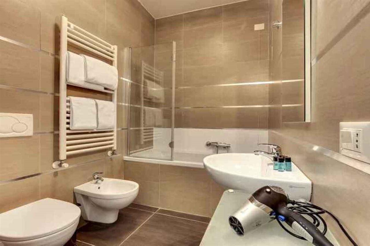 Ein modernes Badezimmer mit einer Badewanne, einem Bidet, einem Handtuchhalter und einem Fön auf der Ablagefläche.