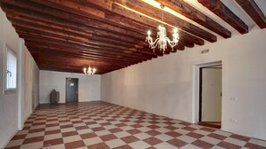 A spacious room with a checkered floor, exposed wooden beams, and a chandelier. - Venice Garden (Venice)
