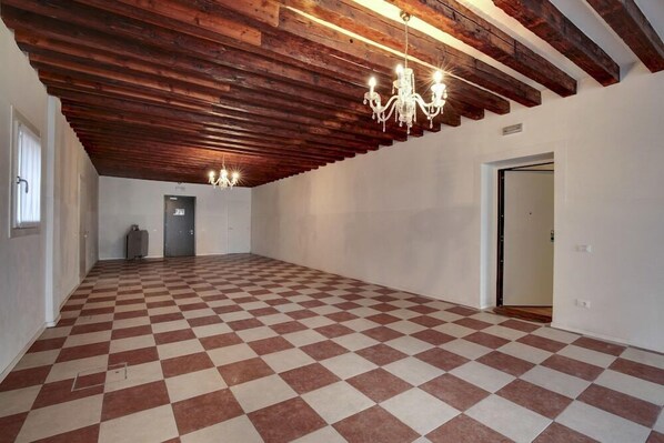 A spacious room with a checkered floor, exposed wooden beams, and a chandelier. - Venice Garden (Venice)