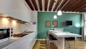 A modern kitchen with white cabinetry, a built-in microwave, and a wooden ceiling. - Venice Garden (Venice)