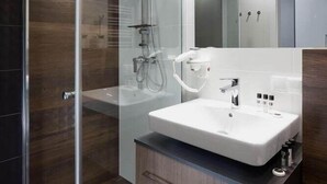 Un baño moderno con ducha envuelta en vidrio, un lavamanos blanco y un espejo encima.