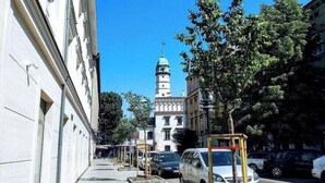 Vista de la calle con un edificio destacado que cuenta con una torre y un cielo azul despejado.