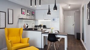 Cocina moderna con armarios blancos, una isla central e iluminación colgante negra.