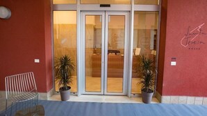 A hotel entrance with a revolving door, potted plants, and a bench. - STH Verona (Verona)