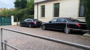 Un camino pavimentado con dos coches negros estacionados frente a un edificio con ventanas protegidas con barrotes.