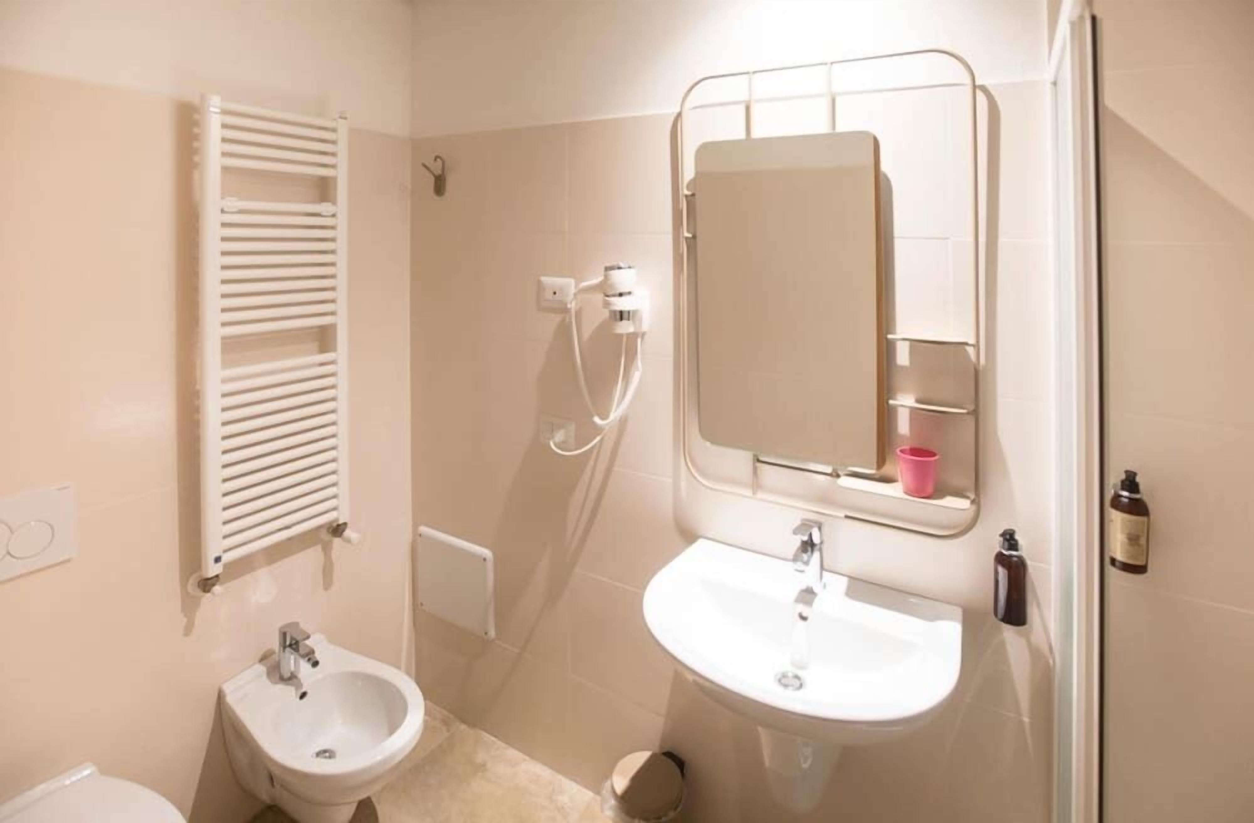 A bathroom with a bidet, a sink, a mirror, and a towel rack.