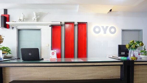 A reception desk with a laptop, a red door, and a sign that reads 'OYO.' - Prince Boulevard Hotel (Manado)