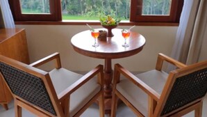A round wooden table with two chairs, a fruit bowl, and two drinks. - D Lobong Suite (Ubud)