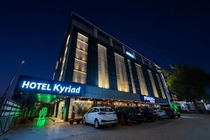 Un hotel llamado 'HOTEL Kyriad' con una fachada moderna, un área de estacionamiento y un escaparate visible con el nombre 'PUNCH'.